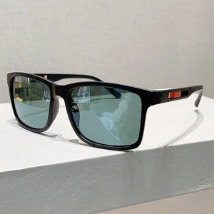 Détail de lunettes de soleil noires mates avec branches à rayures rouges et verres cyan