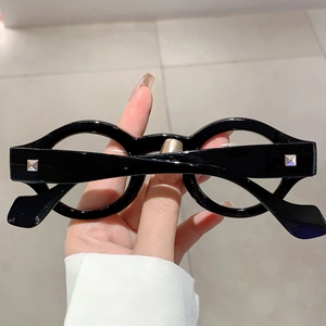 Detailed view of glossy black round eyeglass frame featuring stylish silver square studs
