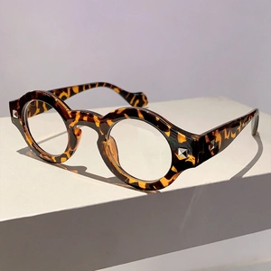 Close-up of retro tortoiseshell round frame glasses with silver rivets on a white stand