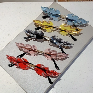 Five pairs of flame-shaped rhinestone sunglasses in assorted colors on a white marble desk