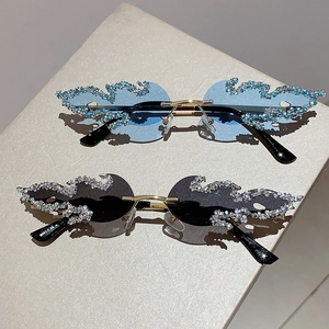 Close-up of flame-shaped rimless sunglasses featuring crystal trim and gold metal bridge