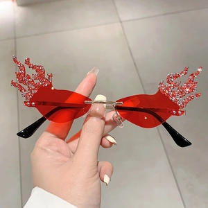 Detail view of flame-shaped sunglasses with red lenses and sparkling rhinestone edges