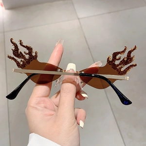 Close-up of flame-shaped rimless sunglasses with rhinestone accents and brown lenses