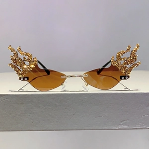 Detail of amber rimless sunglasses featuring gold flame-shaped rhinestone embellishments