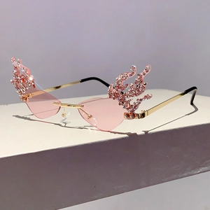 Detail of rimless flame-shaped sunglasses with pink crystal rhinestones and gold metal frames