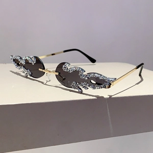 Close-up of frameless flame-shaped sunglasses with sparkling rhinestones and gold metal temples