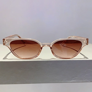 Detail of pink transparent cat eye sunglasses with brown lenses on a geometric stand