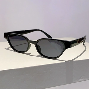 Side view of retro cat-eye sunglasses with glossy black frames on a minimal white stand