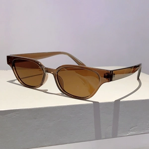 Detail of amber tortoiseshell cat-eye sunglasses with gradient brown lenses on white stand