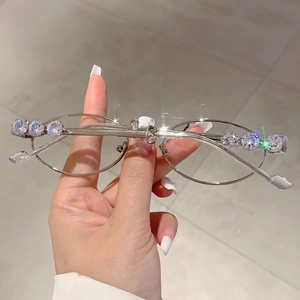 Dettaglio degli occhiali da sole ovali argento con strass scintillanti sulla montatura
