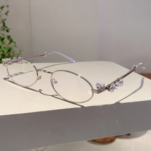 Dettaglio di occhiali da sole ovali argento con strass a cuore scintillanti laterali