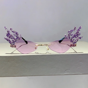 Fashion rimless flame sunglasses with purple rhinestones and tinted lenses on stone base