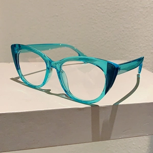 Detail view of transparent blue cat-eye glasses frame on a minimalist white stand