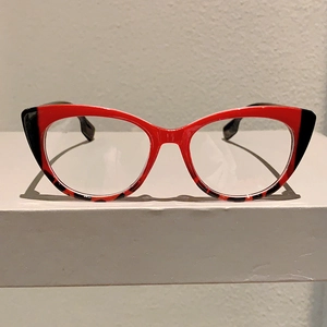 Retro cat-eye glasses frame with red and leopard print patchwork on white surface