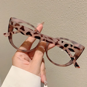 Detail of stylish leopard print glasses frame with pink and black spots in hand