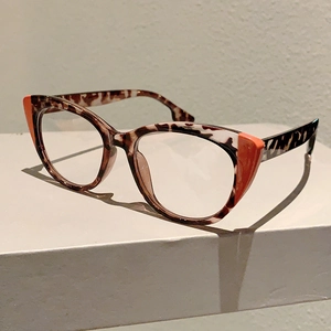 Detail of tortoiseshell cat-eye glasses with orange triangle accents on corners