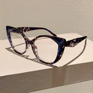 Detail of cat-eye frames with dark blue and brown tortoiseshell texture on a white pedestal