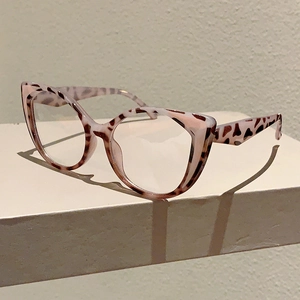 Detailed 45-degree angle of cat-eye leopard print glasses on a geometric stand