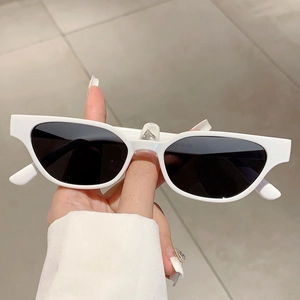 Classic white cat eye sunglasses with dark lenses held by hand showing frame detail