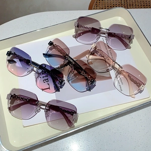 Detail view of rimless sunglasses with gradient lenses and gold chain-link metal temples