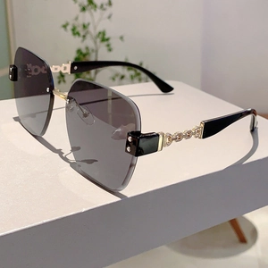 Macro view of frameless sunglasses with gradient lenses and golden metal chain temples