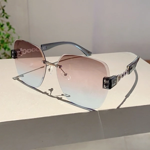Detail of rimless gradient sunglasses featuring gold metal chain temples and cut lenses