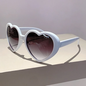 Detailaufnahme der herzförmigen Sonnenbrille mit weißem Rahmen und braunem Verlauf