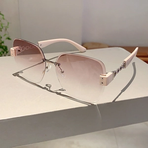 Close-up of rimless square sunglasses with pink gradient lenses and metal chain temples