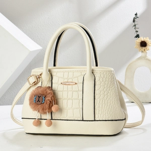 Detail der cremefarbenen Umhängetasche mit Kroko-Prägung und braunem Teddybär-Anhänger