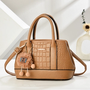 Braune Handtasche mit Krokodilprägung und Bärenanhänger auf minimalistischem Hintergrund