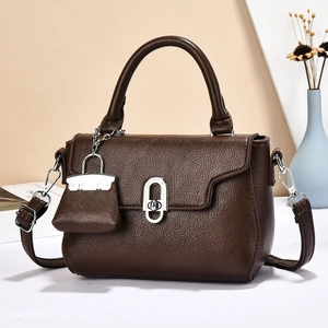 Dark brown pebble leather handbag with silver oval twist lock and mini charm accessory