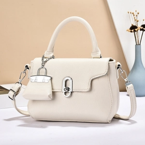 Beige litchi leather handbag with top handle and mini charm, elegant geometric scene