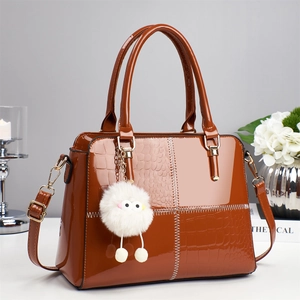 Brown patent leather crossbody bag with croc-embossed detail and plush monster charm