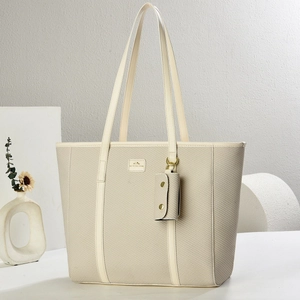 Elegant beige woven tote bag with dual handles and matching small pouch on a minimal backdrop