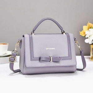 Chic lavender leather crossbody bag with bow detail and gold hardware on white desk