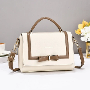Chic beige crossbody bag with brown trim and bow detail in a stylish lifestyle setting