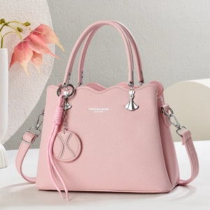 Rosa Lederhandtasche mit Silberbeschlägen und Quastenanhänger vor floralem Hintergrund