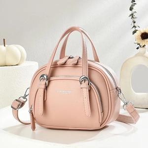 Pink lychee texture crossbody handbag with silver hardware and top handle on white desk