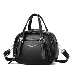Black pebble leather handbag with silver buckles and adjustable strap on white background