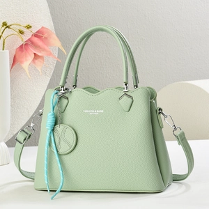 Elegant light green lychee leather handbag with shoulder strap and decorative charm