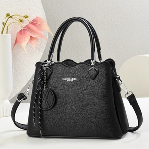 Black pebble leather handbag with wavy edge and crossbody strap on elegant background