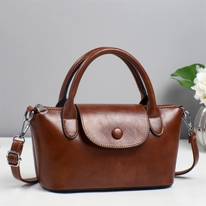 Détail d'un sac à main en cuir marron brillant avec poignées et boucle en métal argenté