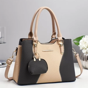 Elegant grey and beige crossbody bag with woven texture and mini charm on white table
