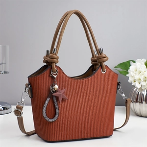 Sac seau terracotta à texture plissée et anses à nœuds marron sur une table blanche