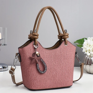 Détail du sac seau plissé rose avec poignée nouée marron et pendentif étoile élégant