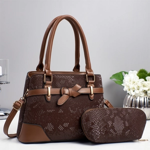 Detail of dark brown snake pattern tote bag with matching crescent pouch and bow accent