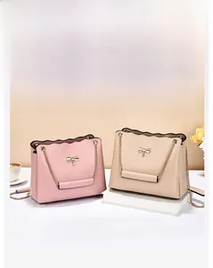 Detail of pink and beige crossbody bags with bow accents and gold chain straps