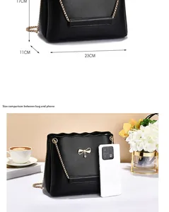 Detail of black crossbody bag with gold bow pendant and chain strap showing dimensions