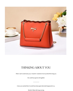 Detail of orange handbag featuring a gold bow pendant and scalloped edge flap