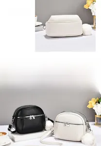 Detailed view of triple-zipper leather crossbody bag with fluffy pompom accessory